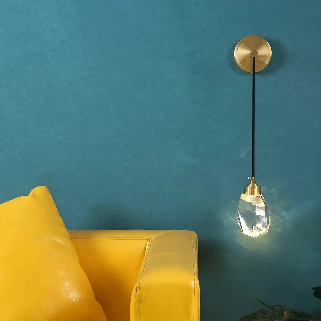 Applique en cristal et laiton sur un mur bleu canard près d'un fauteuil jaune