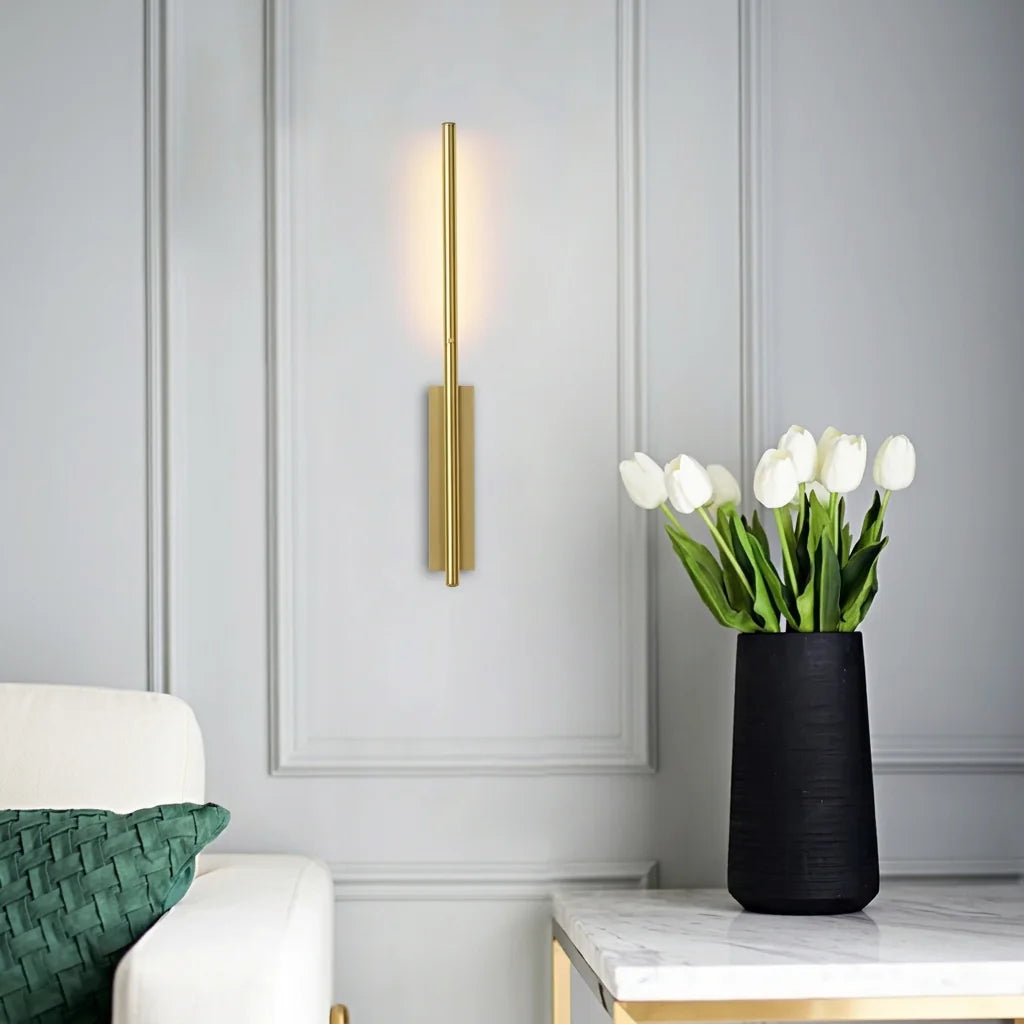 Applique tige LED dorée sur un mur mouluré près d'un bouquet de tulipes