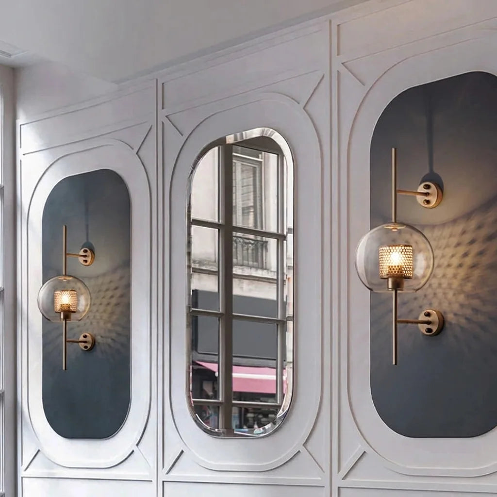 Deux appliques globe à grille sur des panneaux moulurés autour d'un miroir