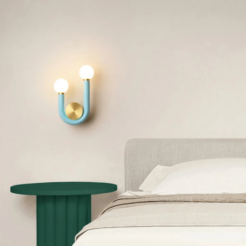 Applique en U bleue au-dessus d'une table de chevet verte cannelée