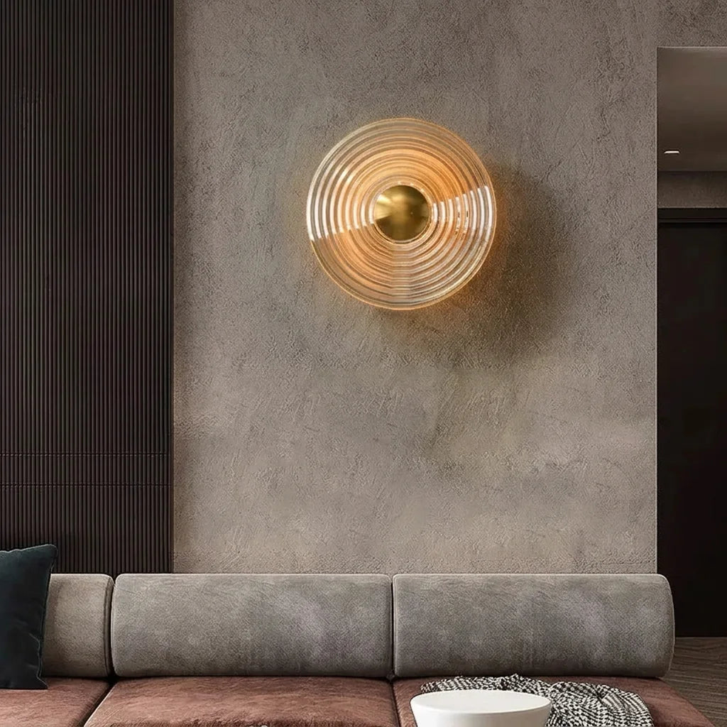 Applique en verre strié au-dessus d'un canapé gris sur un mur en béton ciré