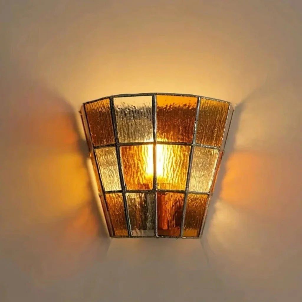 Applique vitrail ambrée projetant des reflets dorés sur le mur