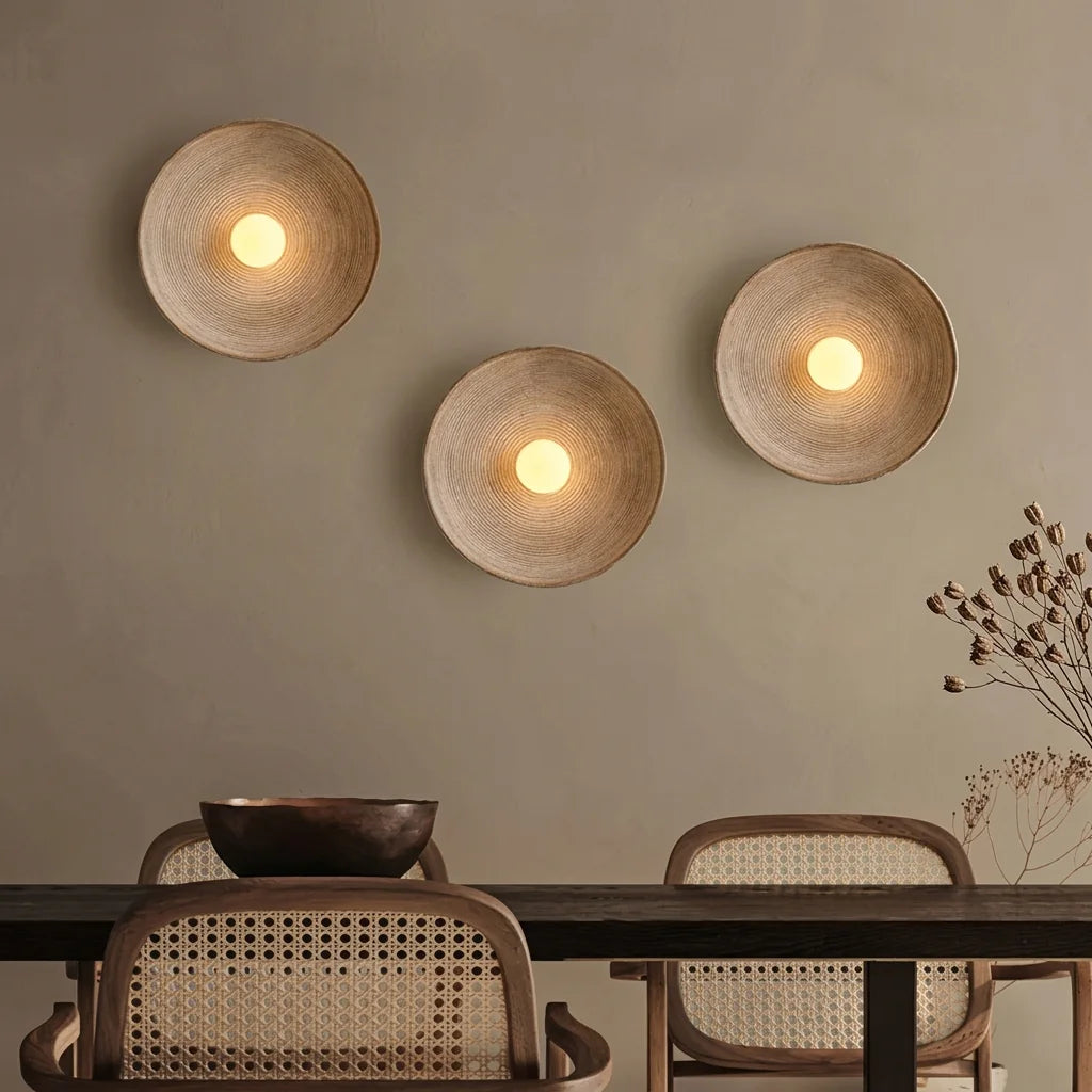Trois appliques coupelle au-dessus d'une table en bois et chaises cannées