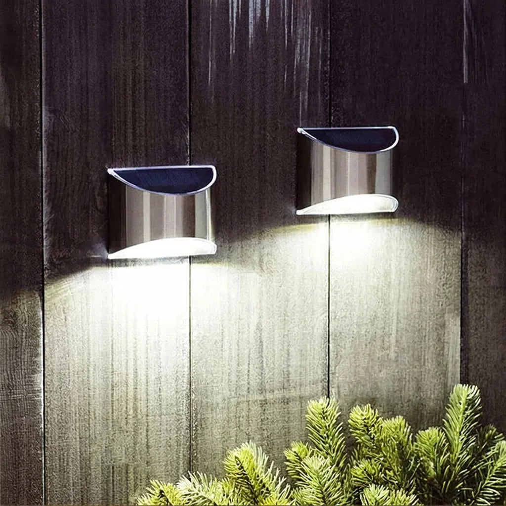 Deux appliques solaires inox éclairant une clôture en bois sombre