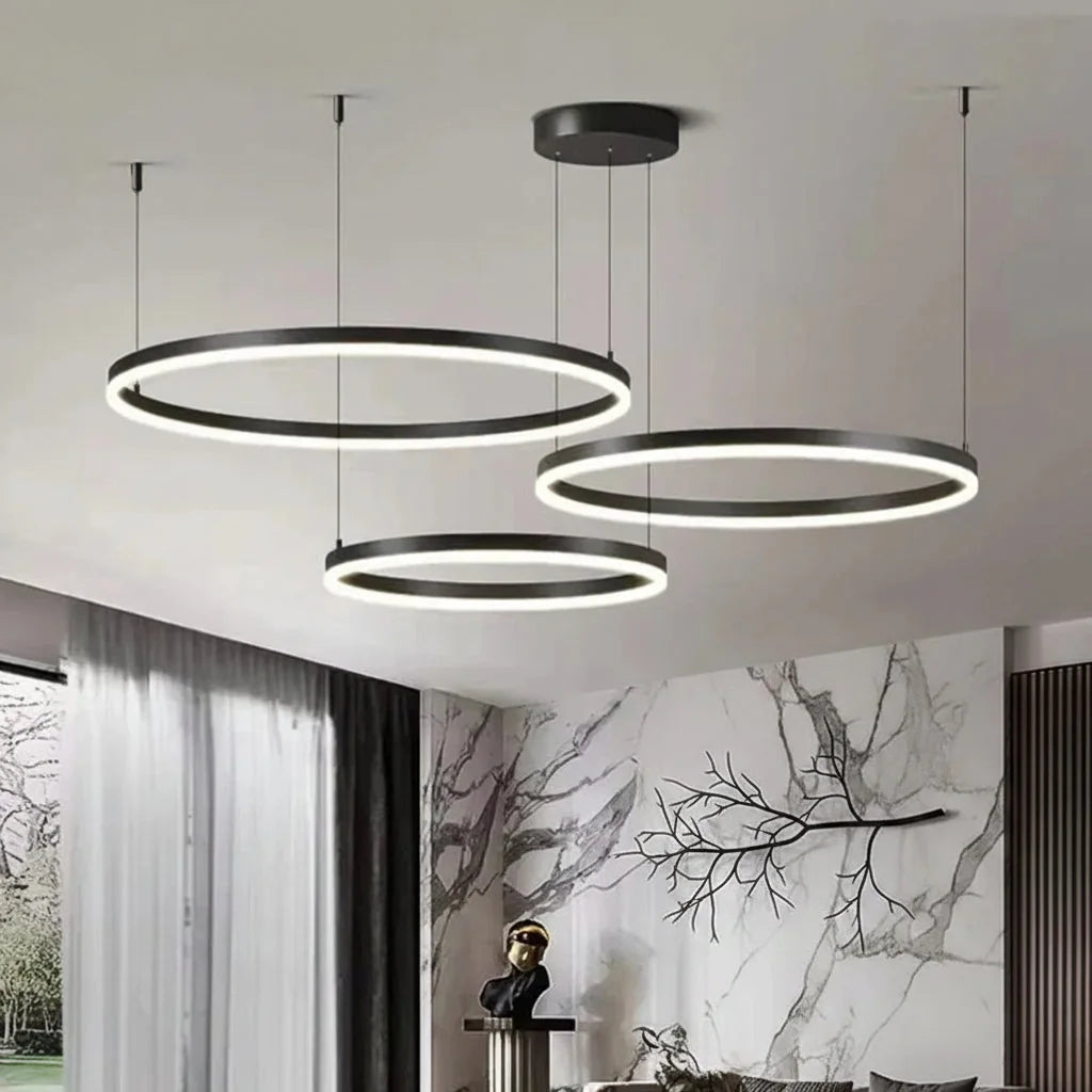 Lustre à anneaux noir dans un salon au mur de marbre