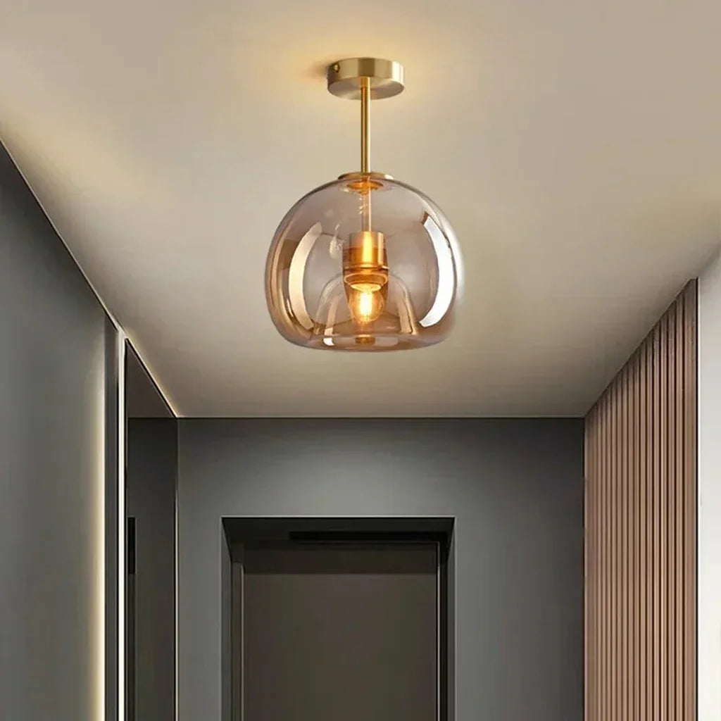 Plafonnier globe en verre cognac sur tige laiton dans un couloir