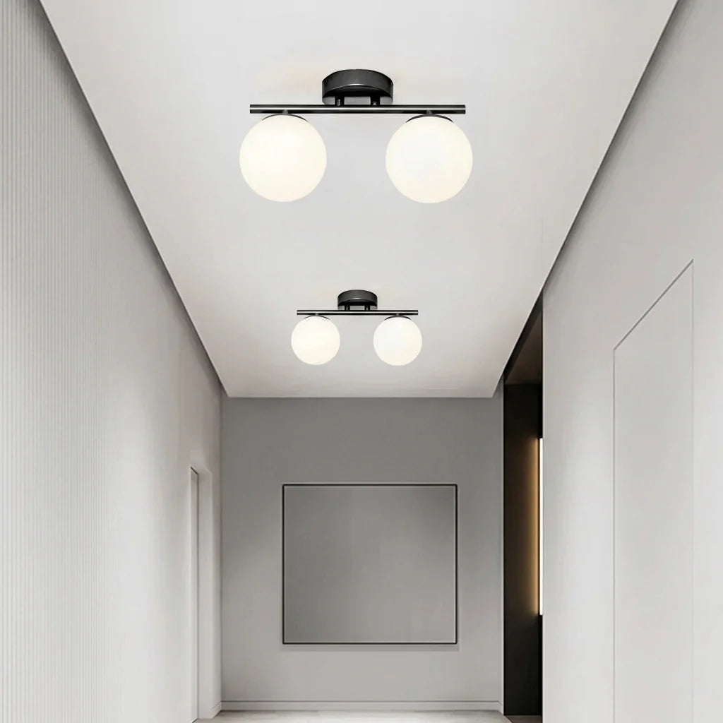 Deux plafonniers noirs à deux globes dans un couloir blanc