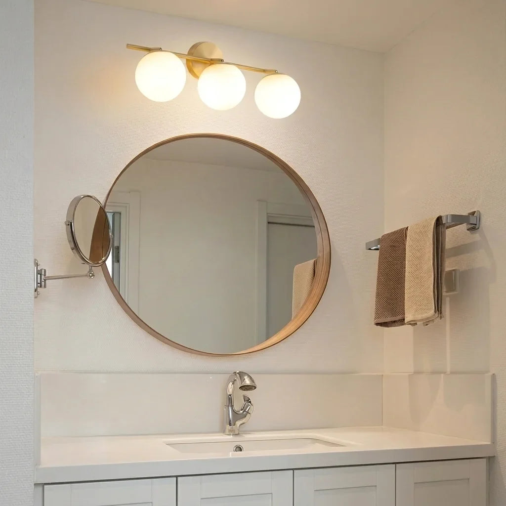 Luminaire doré à trois globes au-dessus d’un miroir rond