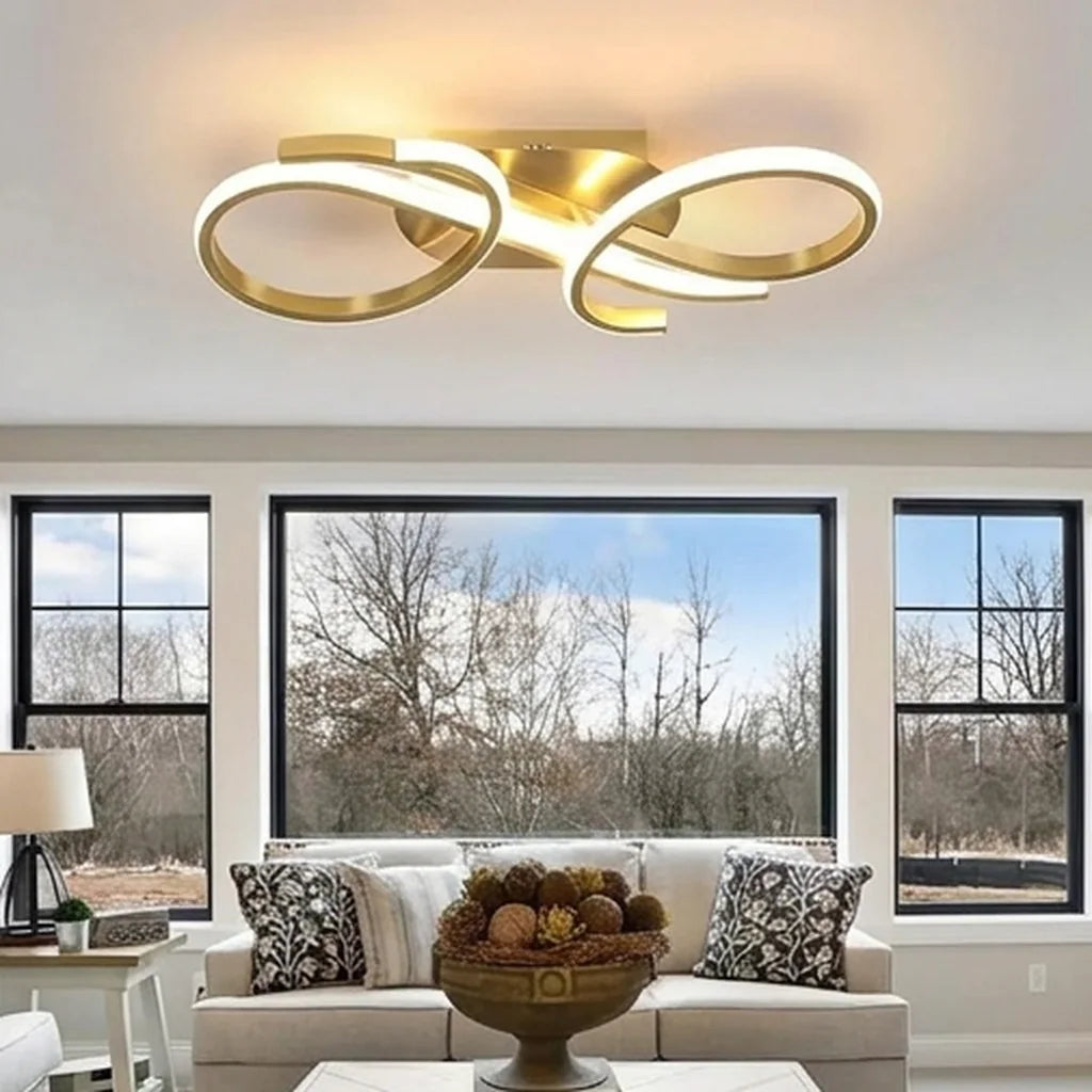 Plafonnier LED doré à boucles dans un salon lumineux