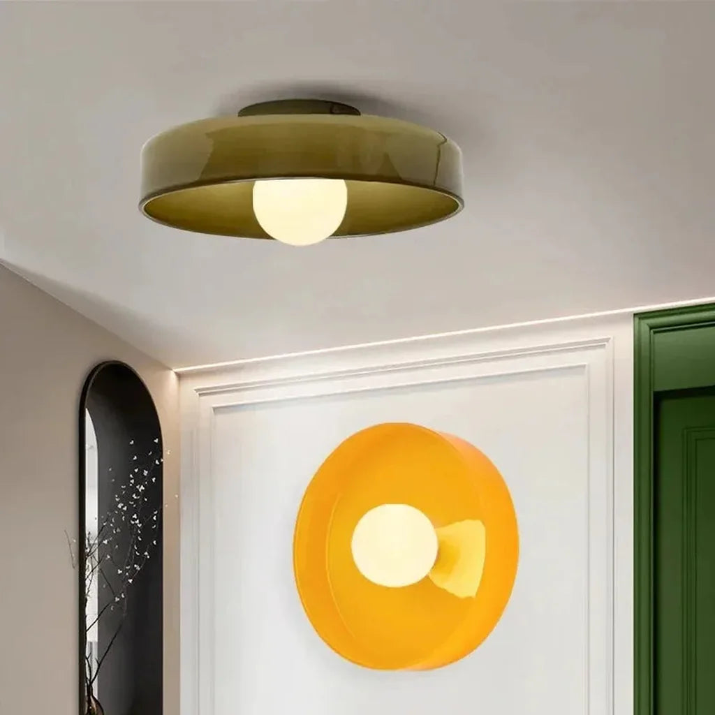 Plafonnier vert et modèle orange fixé au mur dans une entrée à moulures