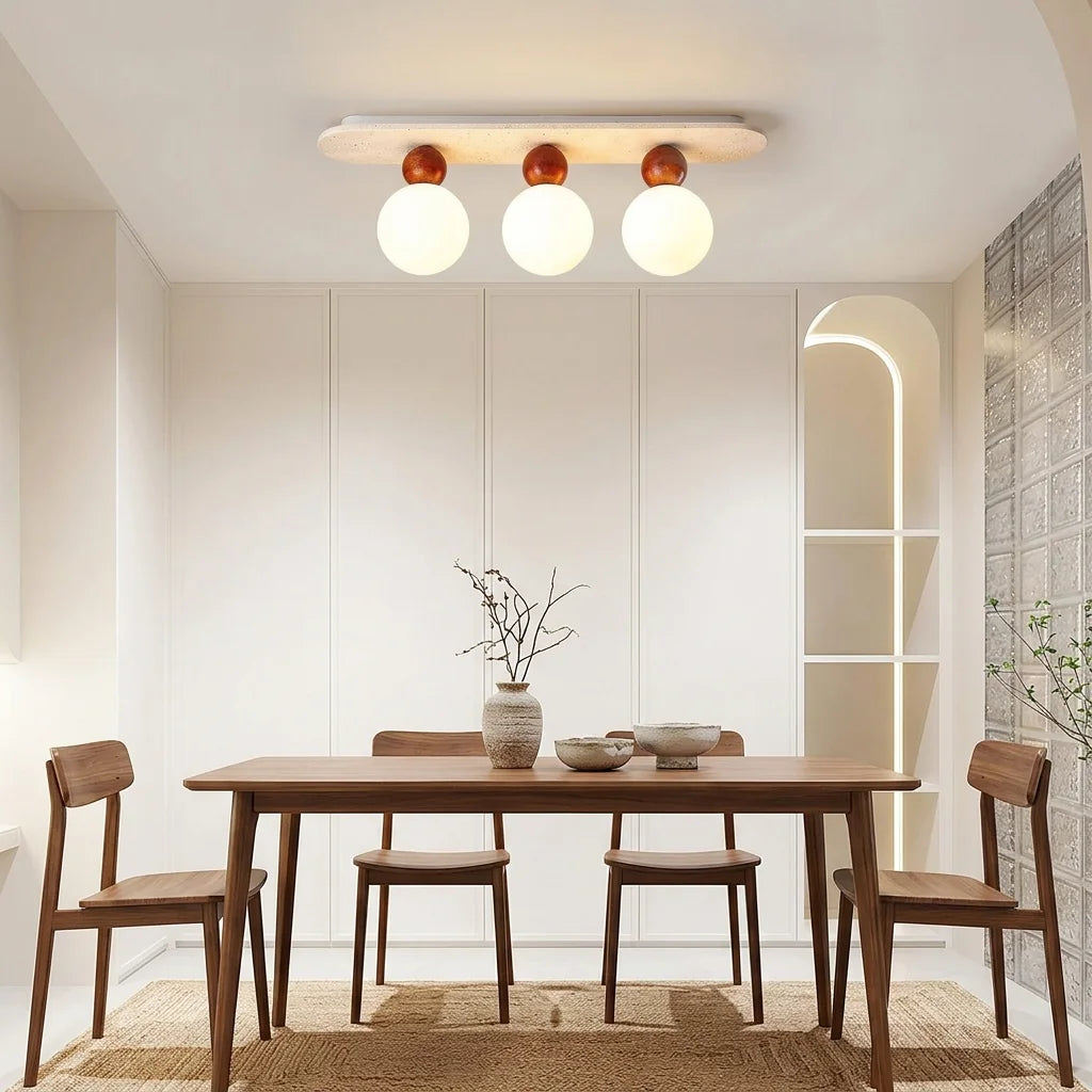 Plafonnier en travertin à trois globes au-dessus d’une table en bois