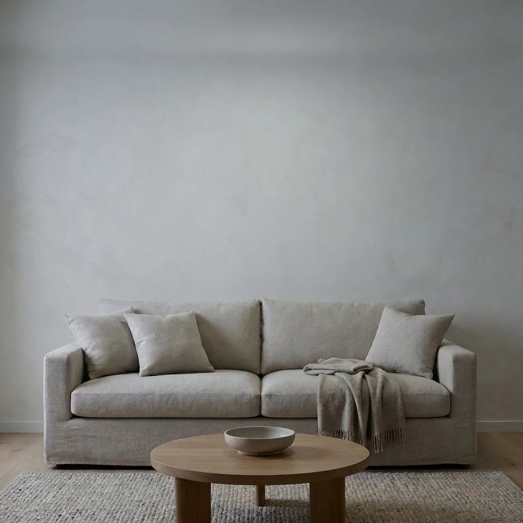 Avant : salon éclairé par un simple plafonnier, mur nu au-dessus du canapé