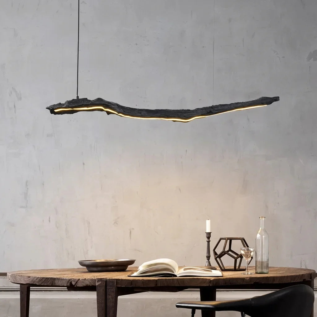 Suspension branche LED au-dessus d’une table rustique, mur en béton